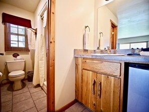 A bathroom with a toilet, sink, and wooden cabinets.