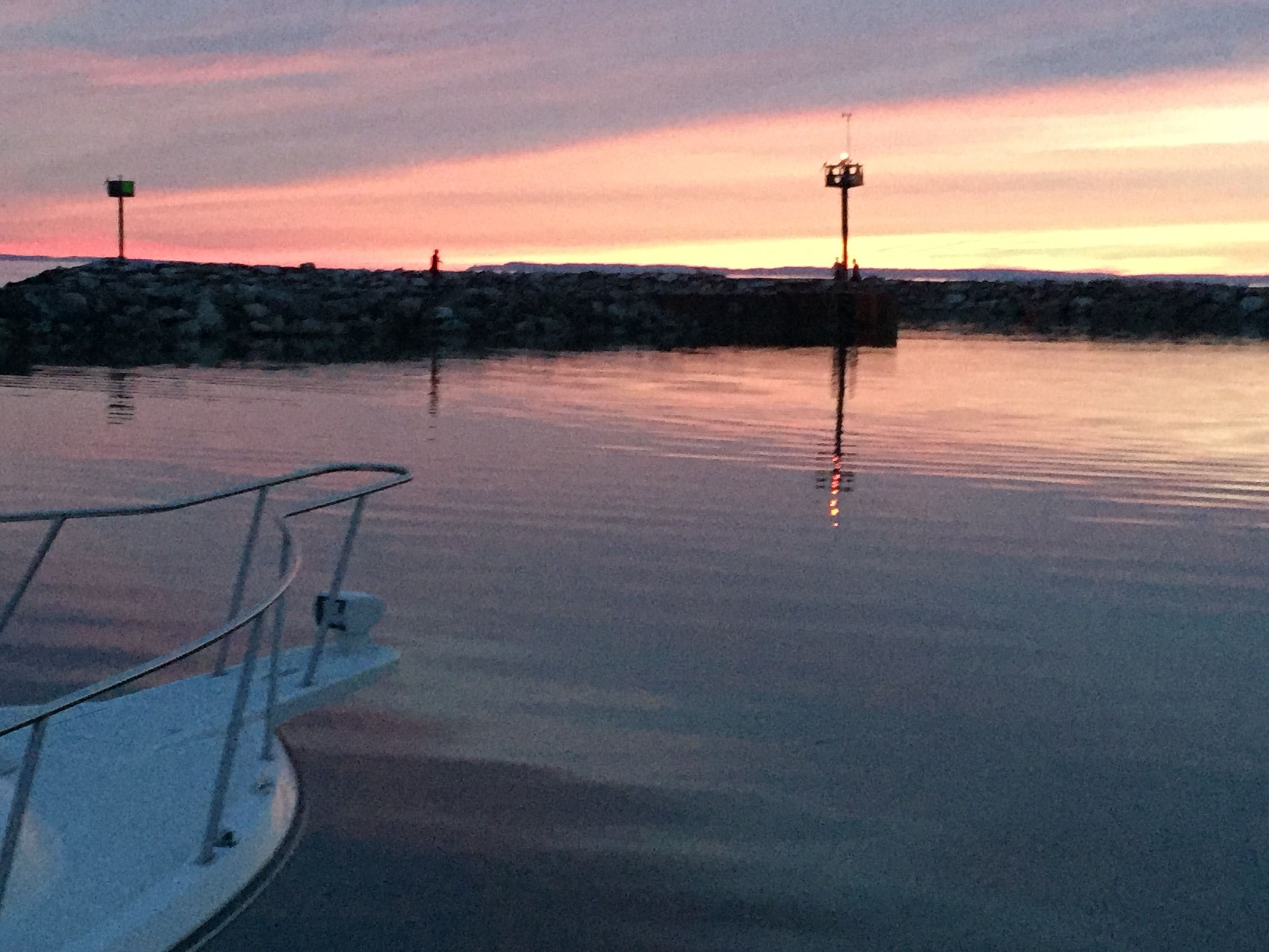 Una orilla tranquila con un muelle para embarcaciones, una escasa y rocosa espigada y dos farolas.
