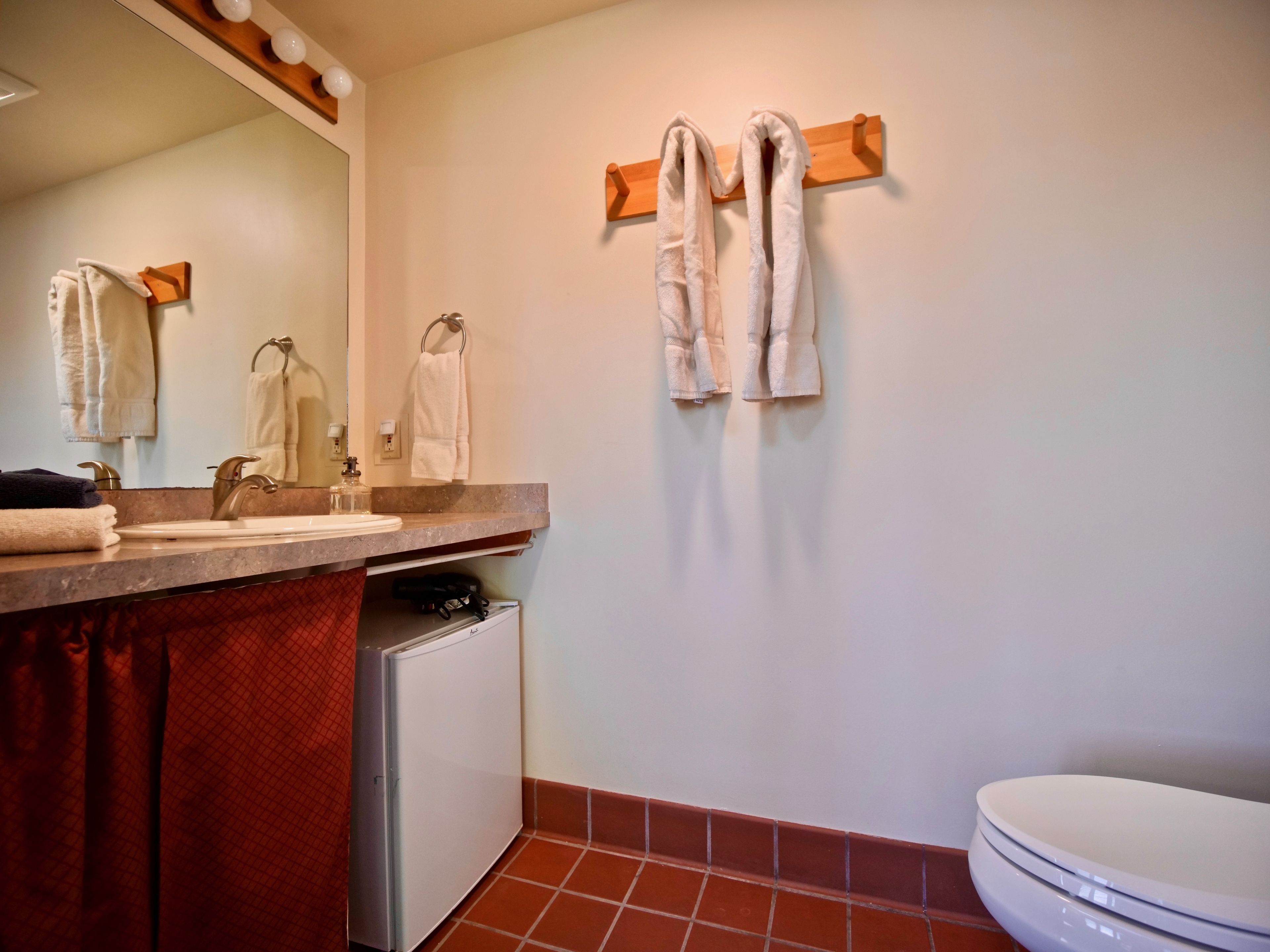 A bathroom with a sink, mirror, towel rack, and toilet.