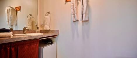 A bathroom with a sink, mirror, towel rack, and toilet.
