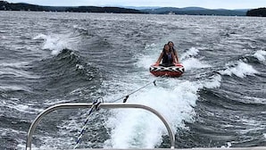A wakeboarding activity on a lake with a boat in the foreground.