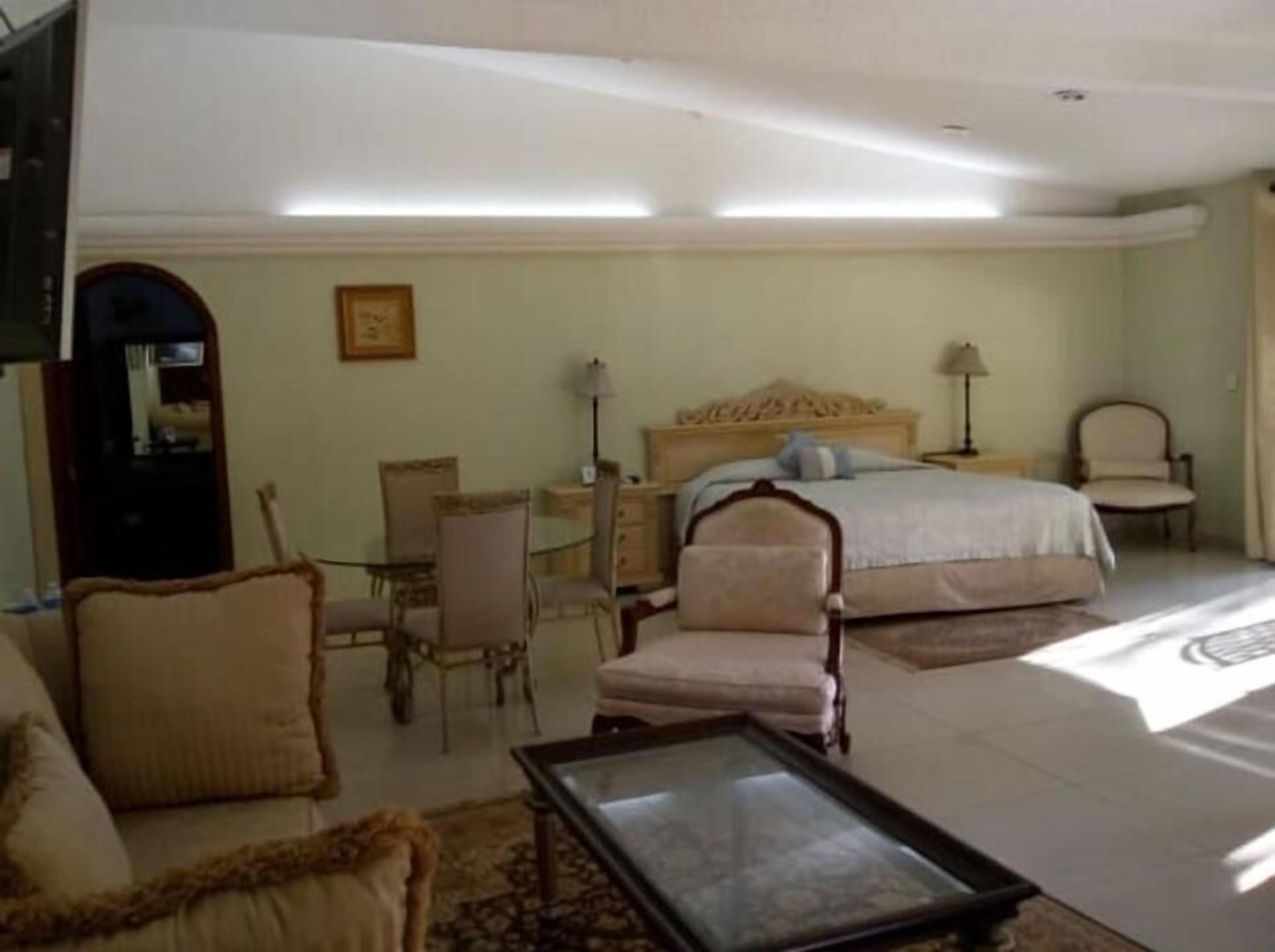 Un dormitorio con una cama, un escritorio, una silla y un sofá.