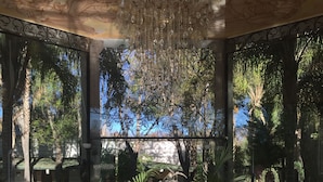 A luxurious lobby with a grand chandelier, a central fountain sculpture, and abundant greenery.