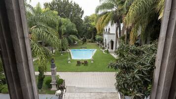 Zona de piscina con vista despejada al jardín circundante y un edificio con columnas.
