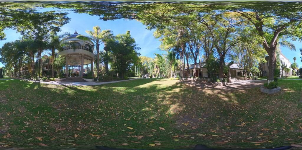Un parque con un pabellón, árboles y un edificio al fondo.