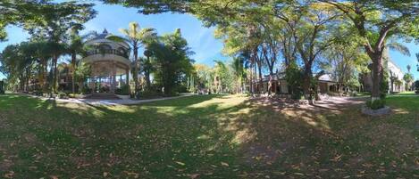 A park with a gazebo, trees, and a building in the background.