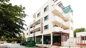 A multi-story building with a white facade, balconies, and a gated entrance. - Lovely Kingsize-bed Studio, amazing rooftop with pool, best location (unit 203) (Playa del Carmen)
