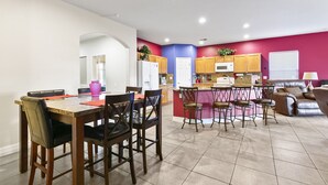 Une cuisine moderne avec un coin repas, comprenant un îlot central, des meubles en bois et une palette de couleurs vives.