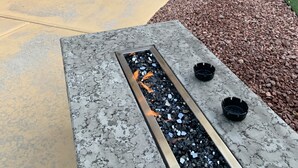 Un espace extérieur aménagé en terrasse, avec un foyer, des sièges et un téléviseur fixé au mur.