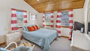 Un dormitorio con cama, mesita de noche, cómoda y televisor.