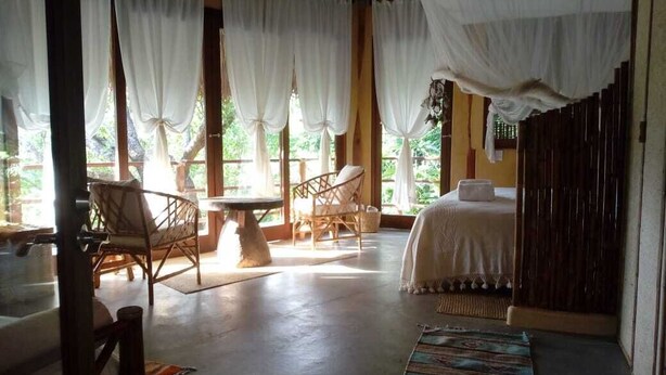 Una habitación con cama, dos sillones, una mesa y una ventana con cortinas.