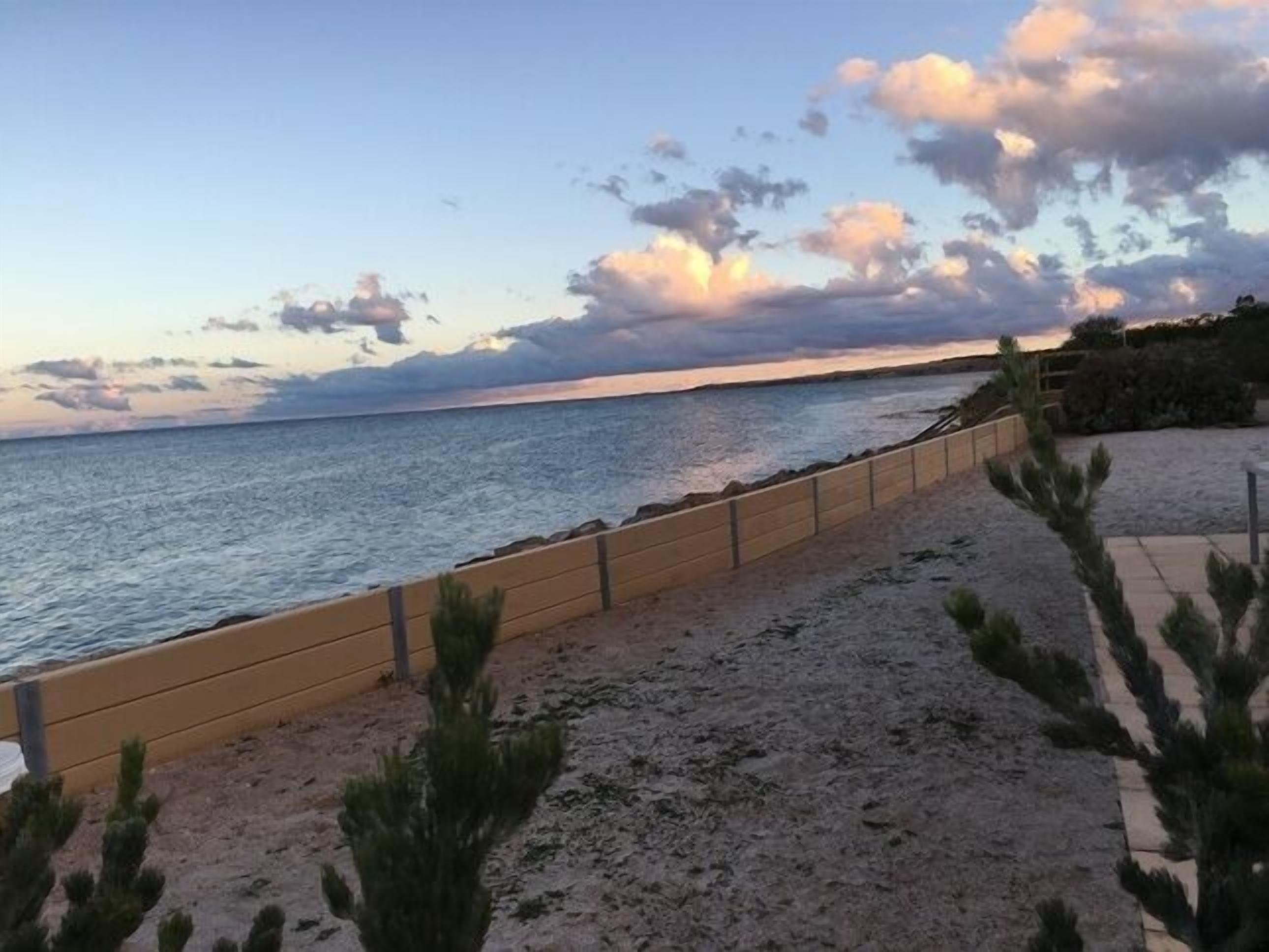 A beach with a wooden walkway and sparse vegetation.