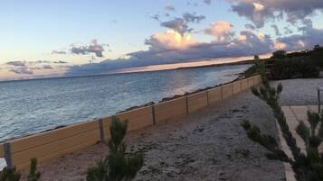 A beach with a wooden walkway and sparse vegetation.