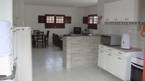 Una cocina con armarios blancos, una isla de piedra y un microondas.