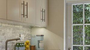 A modern kitchen with stainless steel appliances, a built-in dishwasher, and a window with a view of greenery. - Modern & Spacious Luxury Apartment – Steps to the Beach (Deerfield Beach)