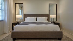 A neatly made bed with white linens, two bedside tables with lamps, and a large mirror on the wall. - Modern & Spacious Luxury Apartment – Steps to the Beach (Deerfield Beach)