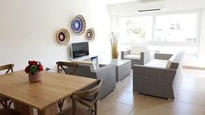 Un salón moderno con una mesa de comedor de madera, muebles de mimbre y platos decorativos en la pared.