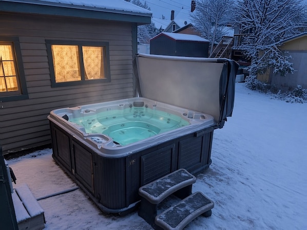 A hot tub with a cover, steps, and a house in the background. - Governor's Mansion Main — 4BR Sleeps 8, Pool Table, Sauna, Walk to Main St (Leadville)