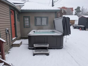 A hot tub in a snowy backyard with a house in the background. - Governor's Mansion Main — 4BR Sleeps 8, Pool Table, Sauna, Walk to Main St (Leadville)
