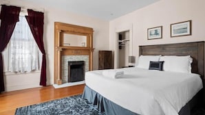 Una habitación de hotel con una cama grande, una chimenea, un armario y un espejo.