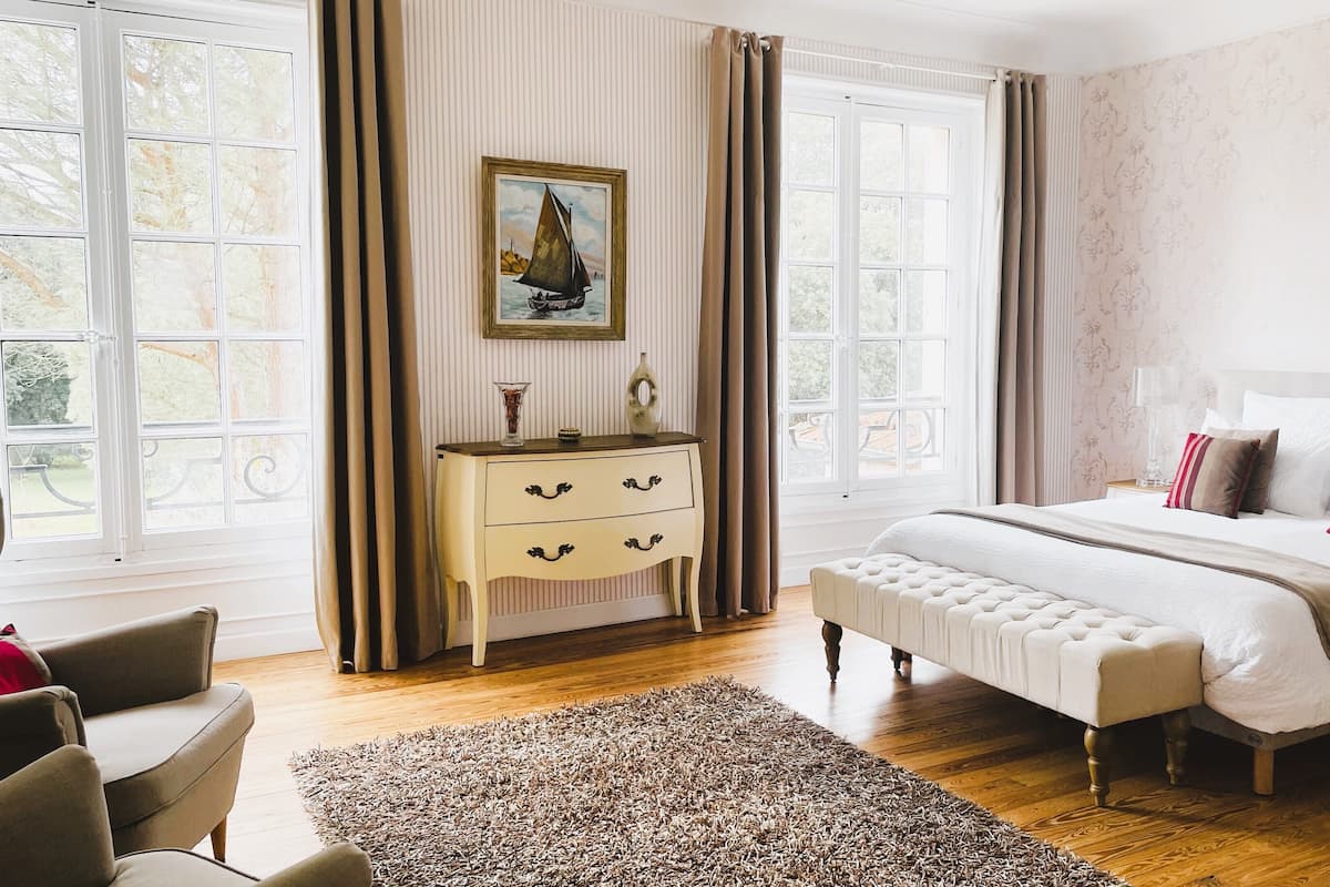 A bedroom with a large bed, a dresser, and a painting on the wall.