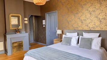 A bedroom with a bed, a nightstand, a fireplace, and a door.