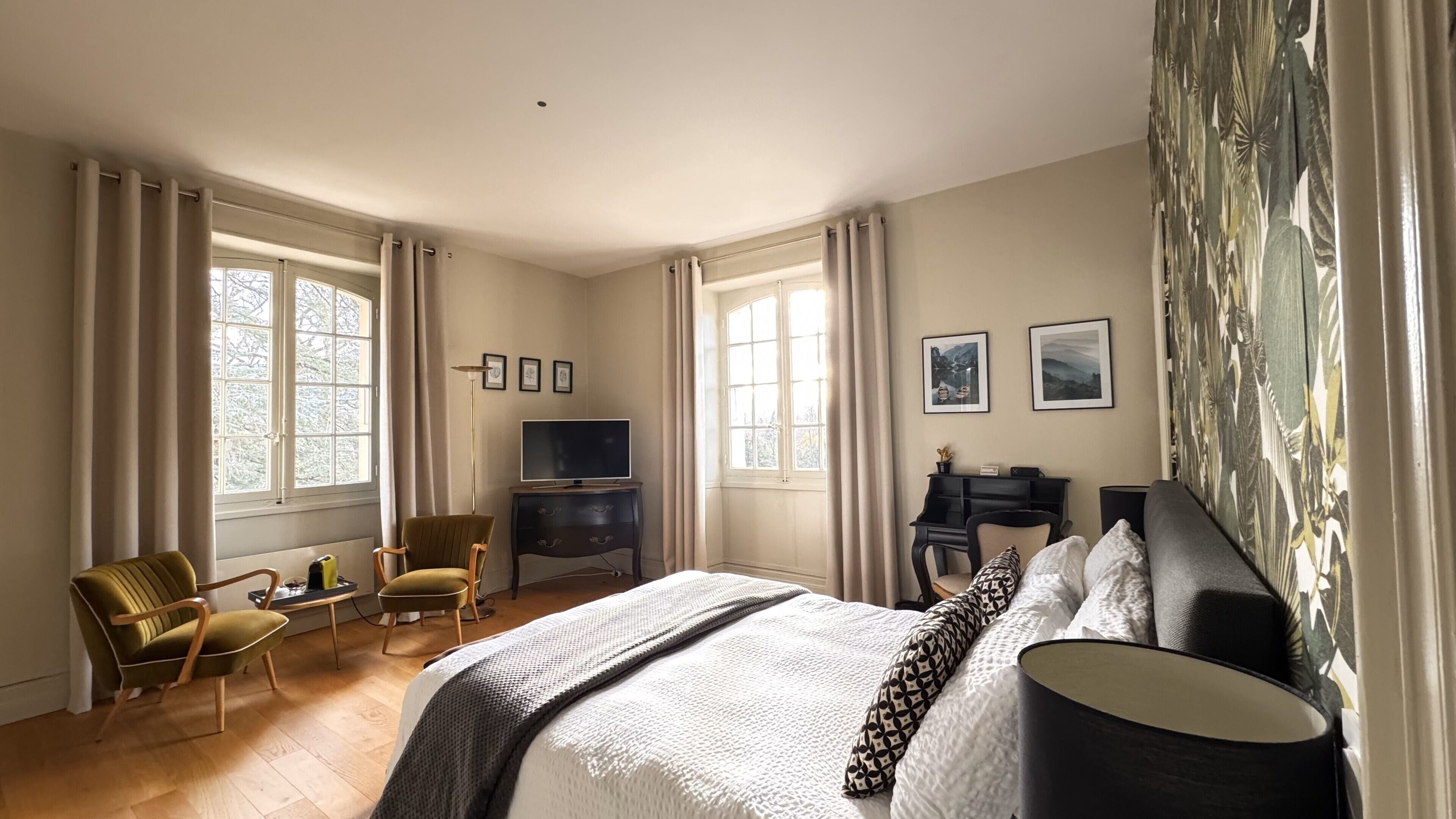 A hotel room with a large bed, a desk with a computer, a chair, and a TV.