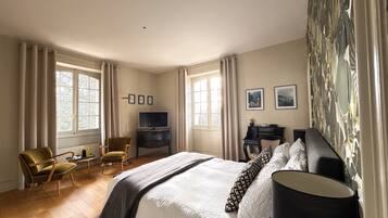 A hotel room with a large bed, a desk with a computer, a chair, and a TV.