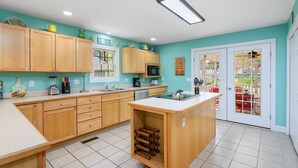 Une cuisine avec des meubles de rangement en bois, un îlot central, un four à micro-ondes et un évier.