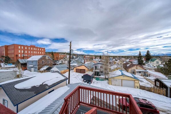 A residential neighborhood with snow-covered roofs and houses, a red building, and a clear sky.