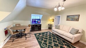 Ein gemütliches Wohnzimmer mit rundem Tisch, beiger Couch und Fernseher, der Streamingdienste anzeigt.