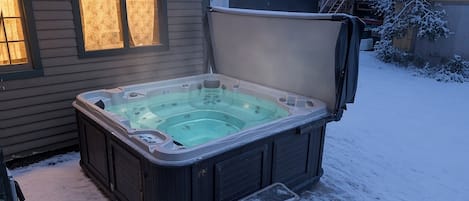 Un jacuzzi con tapa, escalones y una casa al fondo.