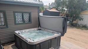 Ein Whirlpool mit Stufen, ein Haus mit Fenster und ein Baum.