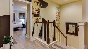 A staircase with a wooden handrail and a mural on the wall. - Single Malt Manor | Downtown Austin (Austin)