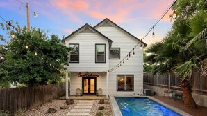 A two-story house with a pool, a wooden fence, and string lights. - Single Malt Manor | Downtown Austin (Austin)