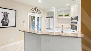A modern kitchen with white cabinetry, a marble countertop, and stainless steel appliances. - Single Malt Manor | Downtown Austin (Austin)