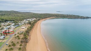 A coastal area with a sandy beach, a small settlement with houses and a road, and a large body of water.