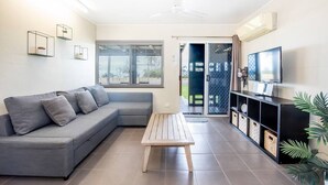 A modern living room with a grey sectional sofa, a wooden coffee table, and a black entertainment unit.