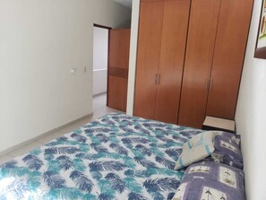 A bedroom with a bed, a wardrobe, and a door leading to another room.