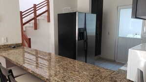 A kitchen with granite countertops, a black refrigerator, and a white sink. - Beautiful house in Acapulco Diamante, come and enjoy. Hermosa casa en Acapulco (Granjas del Marqués)