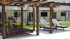 A covered outdoor seating area with a swing, two lounge chairs, and a wooden deck. - Beautiful house in Acapulco Diamante, come and enjoy. Hermosa casa en Acapulco (Granjas del Marqués)