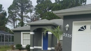 Une maison d’habitation avec une porte bleue, le numéro 2535, un petit jardin devant et un chemin menant à l’entrée.