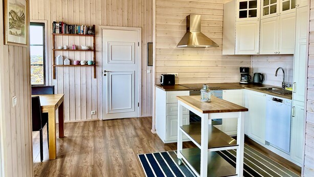 A compact kitchen with wooden walls, a built-in stove, and white cabinets.