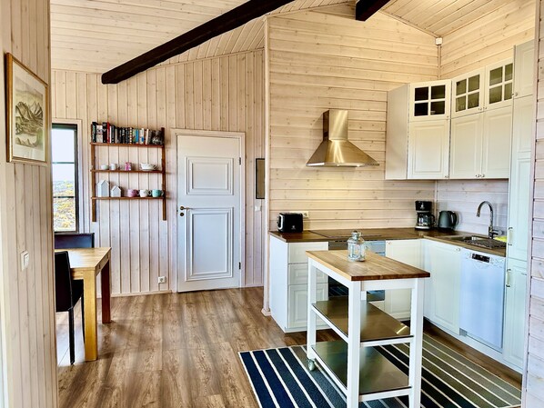A compact kitchen with wooden walls, a built-in stove, and white cabinets.