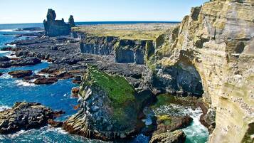 A coastal landscape with rocky cliffs and a clear view of the ocean.