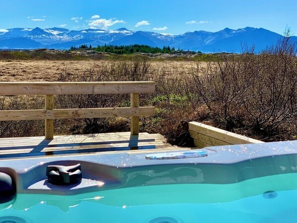 Un bain à remous avec une terrasse en bois et une vue sur les montagnes.