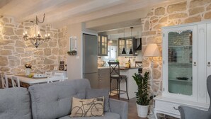 Una sala de estar moderna con un sofá gris, una mesa de comedor y una cocina al fondo.