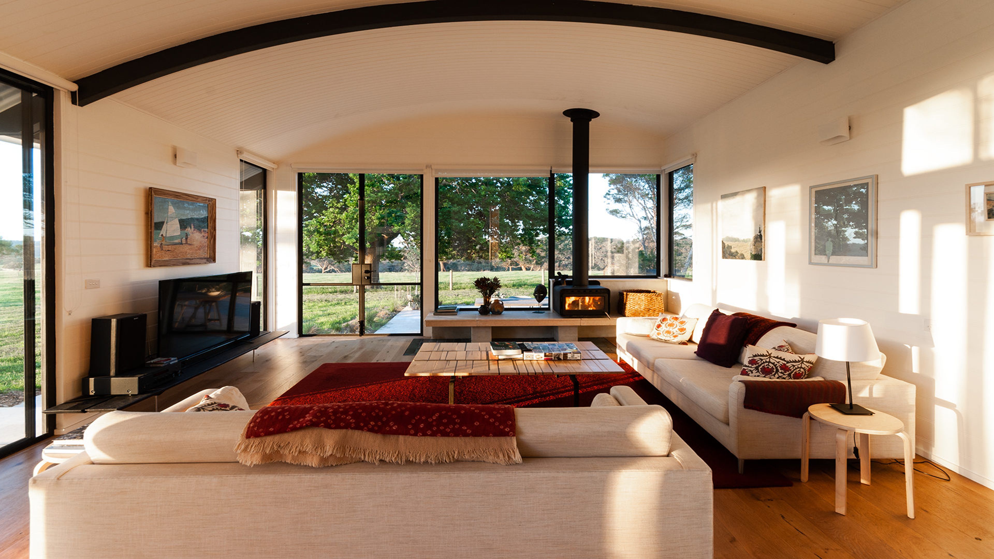 A modern living room with a fireplace, large windows, and a cozy seating area.