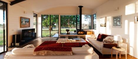 A modern living room with a fireplace, large windows, and a cozy seating area.