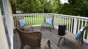 A covered outdoor deck with wicker furniture and a small round table.
